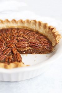 Front view of a pecan pie with a slice removed.