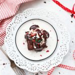 Overhead view of a gluten free, dairy free peppermint brownie sundae with vanilla cashew milk ice cream, vegan hot fudge sauce and red, white, and green sprinkles.