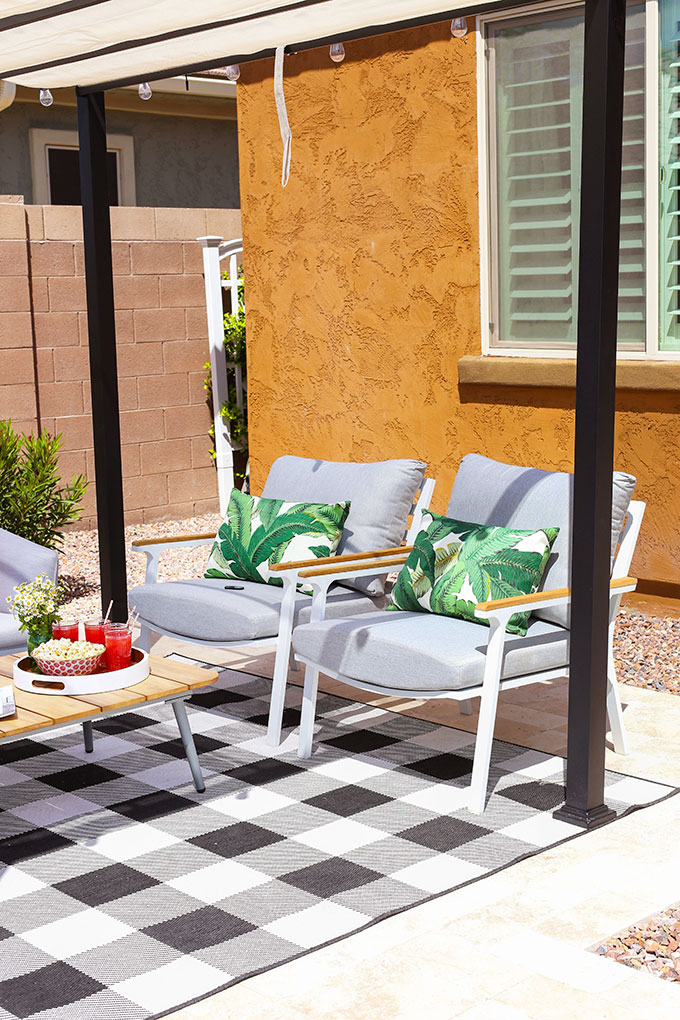 Elena Cera Gray Lounge Chairs from Article styled with banana leaf lumbar pillows and a black and white gingham outdoor rug
