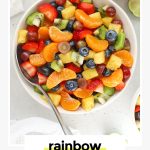 a large white serving bowl of colorful fruit salad with all the colors of the rainbow