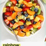 a large white serving bowl of rainbow fruit salad