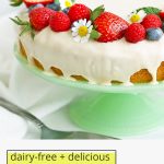Close up front view of gluten-free lemon cake with lemon glaze topped with fresh berries with text overlay that reads "dairy-free + delicious gluten-free lemon cake with lemon vanilla glaze"