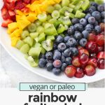 Front view of rainbow fruit salad with text overlay that reads "vegan + paleo rainbow fruit salad with citrus mint dressing"