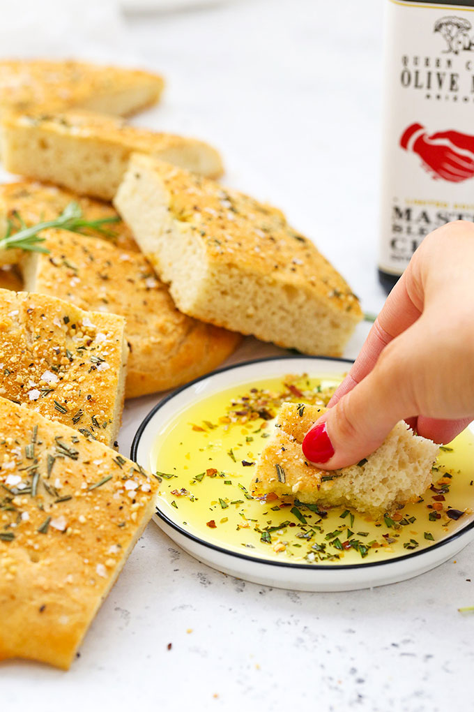 Dipping gluten free focaccia into olive oil and fresh herbs