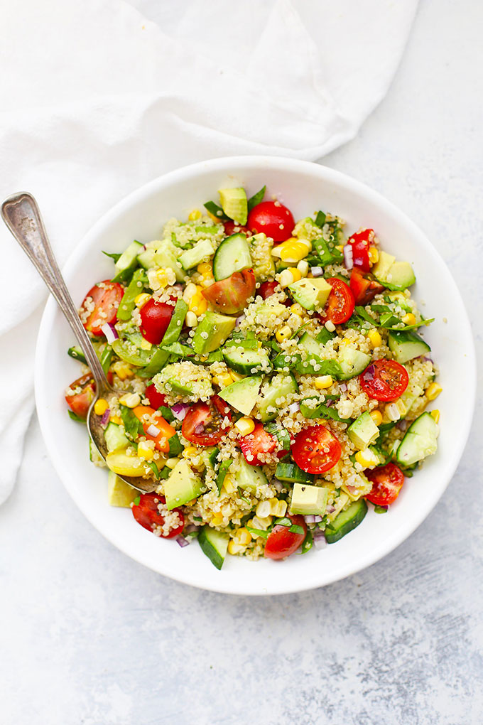 White bowl of Farmers' Market Quinoa Salad with sweet corn, avocado, cucumber, and tomatoes.