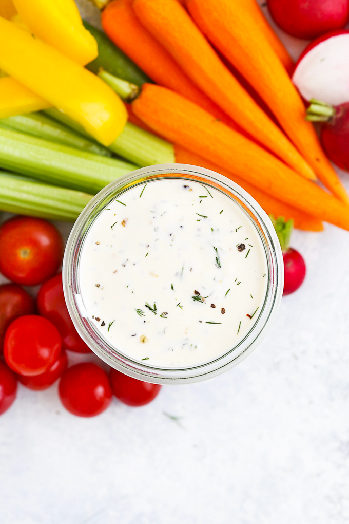 Close up overhead view of paleo ranch dressing with fresh veggies in the background