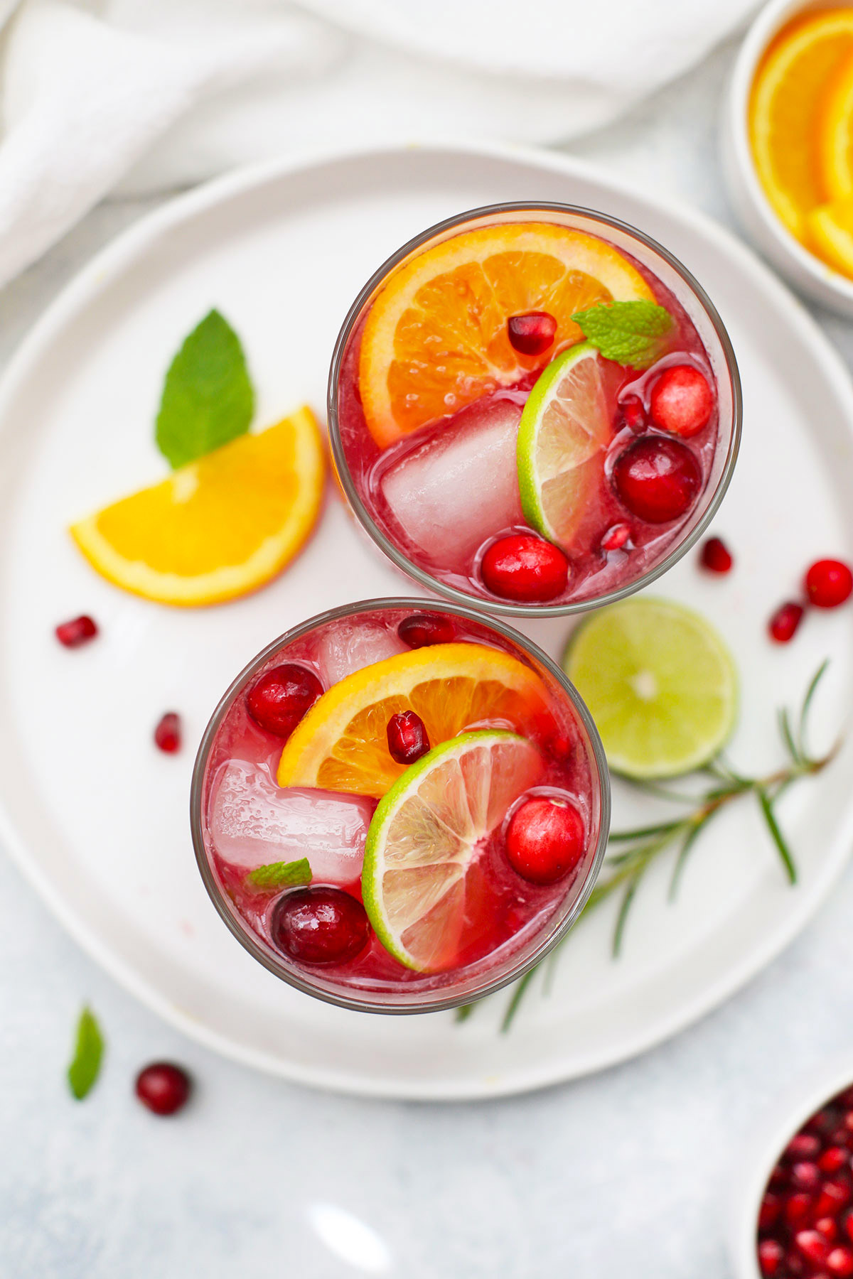 Overhead view of Two Non-alcoholic sparkling citrus pomegranate mocktails on a white plate