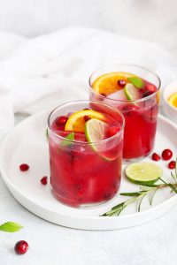 Two Non-alcoholic sparkling citrus pomegranate mocktails on a white plate