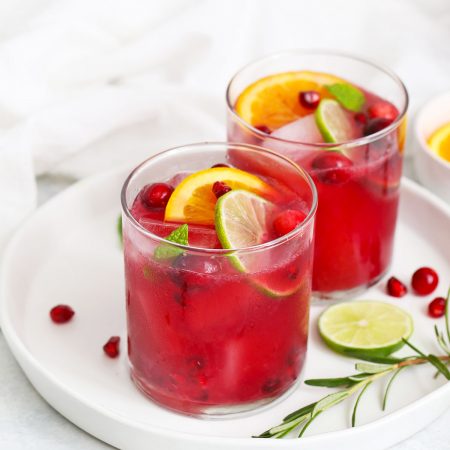 Two Non-alcoholic sparkling citrus pomegranate mocktails on a white plate