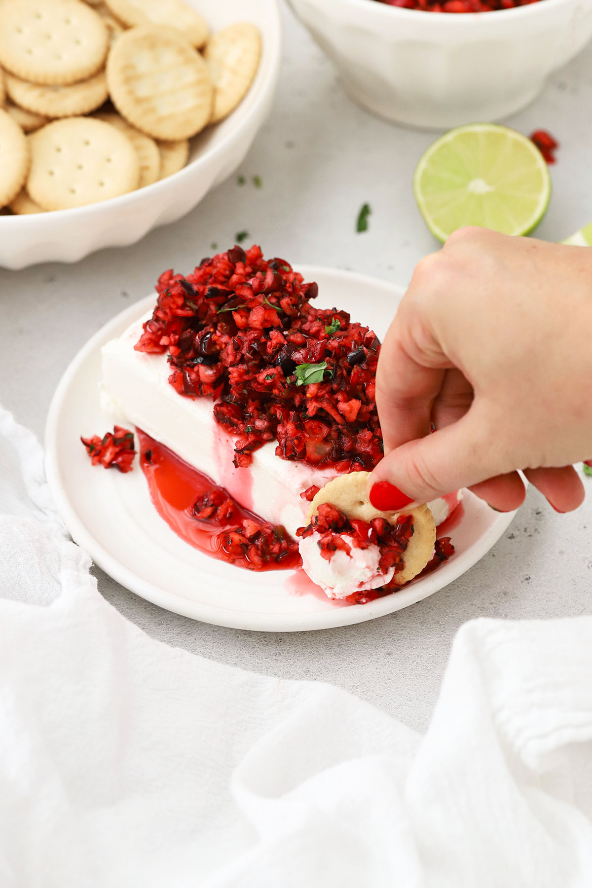 dipping crackers into cranberry salsa cream cheese appetizer