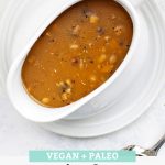 Close Overhead view of a white gravy boat full of paleo and vegan mushroom gravy from One Lovely Life with text overlay that reads "Vegan + Paleo Simple Mushroom Gravy. Hearty + Savory + Delicious!"