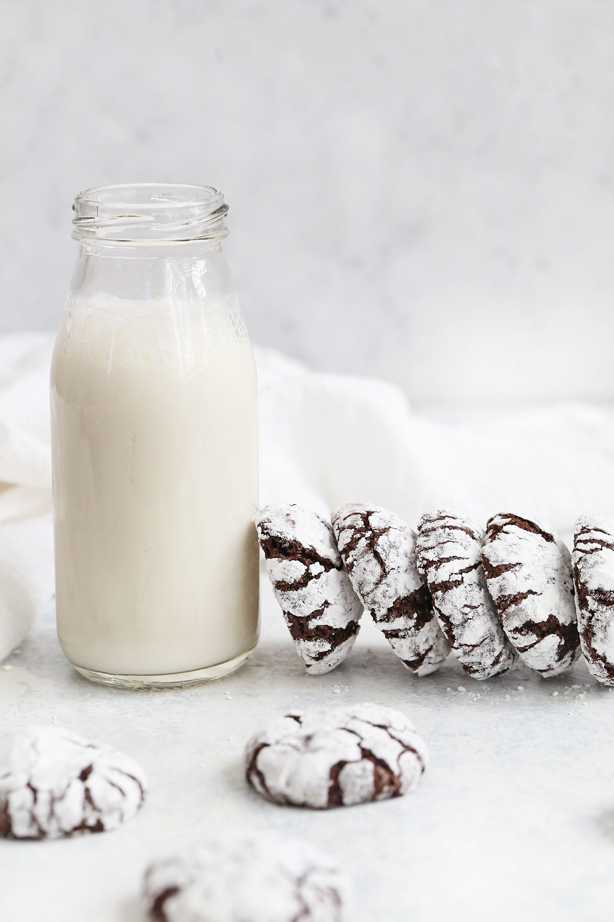 Front view of gluten-free chocolate crinkle cookies leaning against a bottle of almond milk