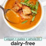 Overhead view of a bowl of dairy free tomato basil soup with text overlay that reads "vegan + paleo + whole30 dairy-free tomato basil soup: warm + cozy + smooth"