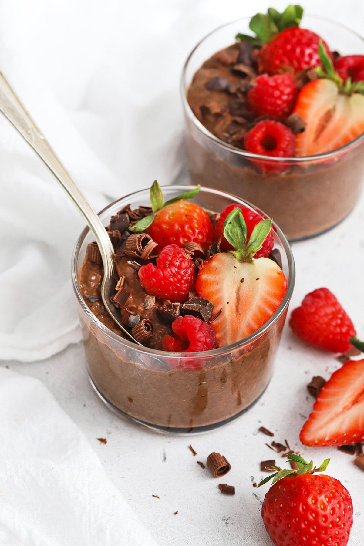 Front view of two bowls of healthy chocolate chia pudding topped with fresh berries and shaved chocolate