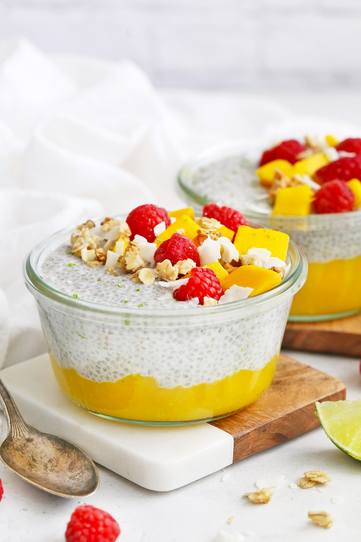 Close Up Front View of Jars of Mango Chia Pudding Topped with Raspberries, Granola, and Fresh Mango