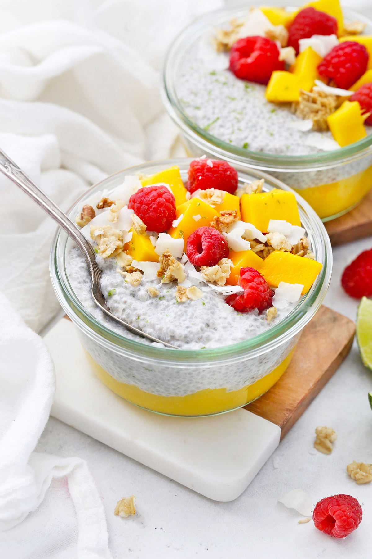 Front View of Jars of Mango Chia Pudding Topped with Raspberries, Granola, and Fresh Mango