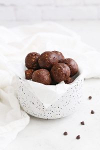 Front view of almond joy energy bites in a speckled white bowl.