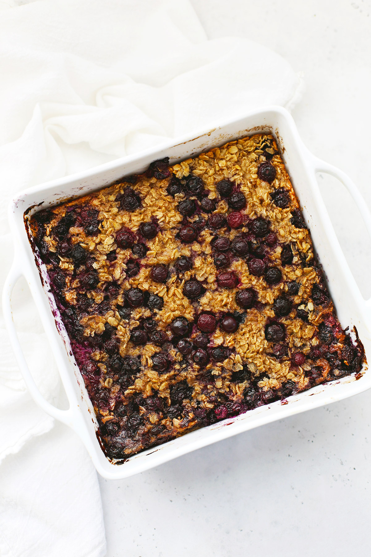 A white baking dish of blueberry baked oatmeal on a white background