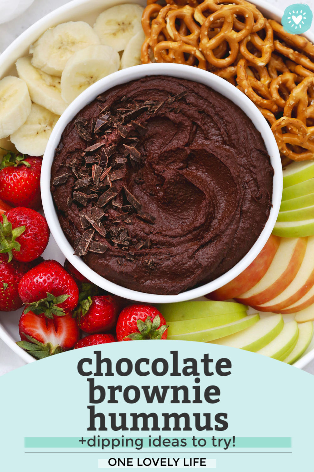 Overhead view of a bowl of chocolate brownie hummus on a fruit plate with text overlay that reads "Chocolate brownie hummus +dipping ideas to try! One Lovely Life"