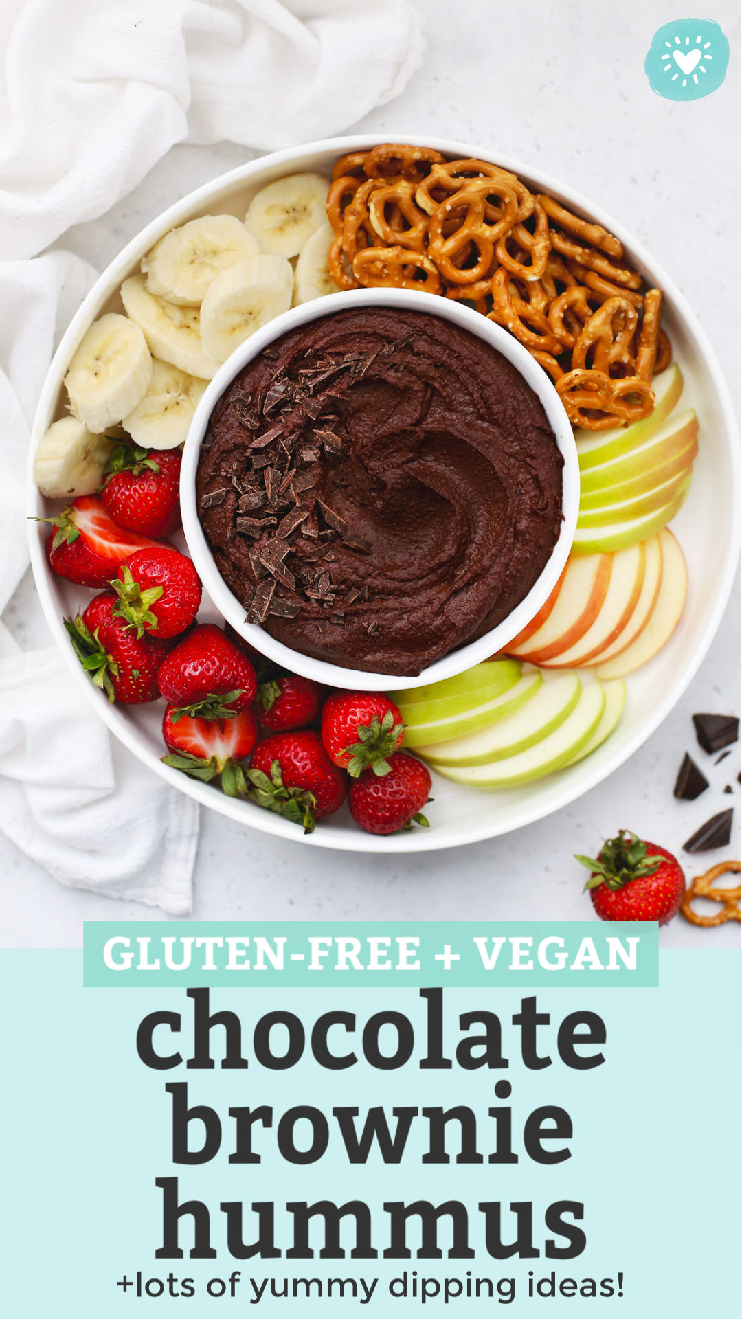 Overhead view of a bowl of chocolate brownie hummus on a fruit plate with text overlay that reads "Gluten-Free + Vegan Chocolate Brownie Hummus +lots of yummy dipping ideas"