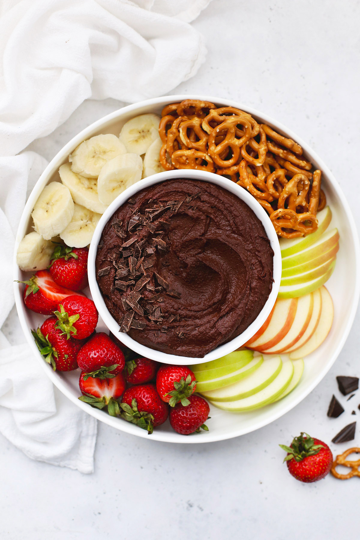 Overhead view of a bowl of chocolate brownie hummus on a fruit plate