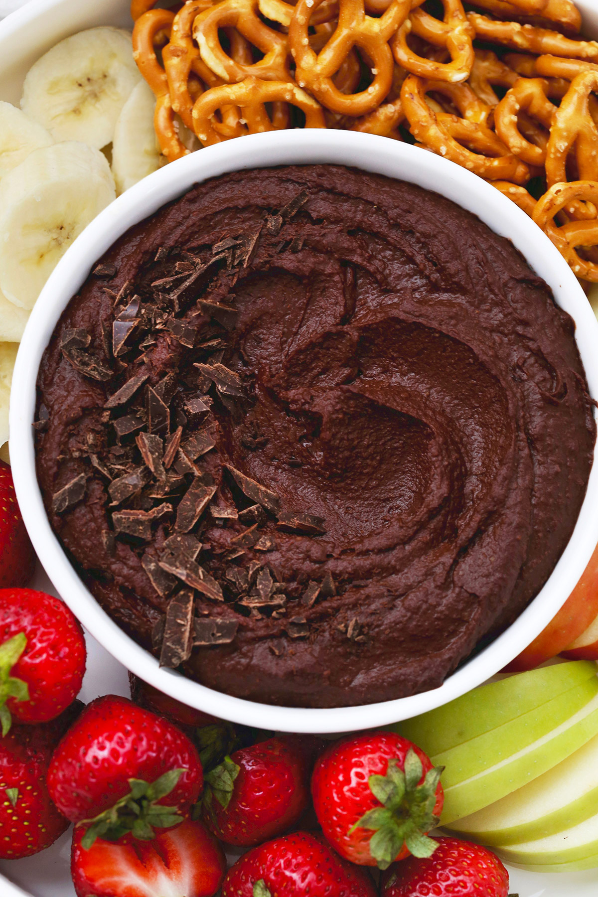 Close overhead view of a bowl of chocolate brownie hummus on a fruit plate