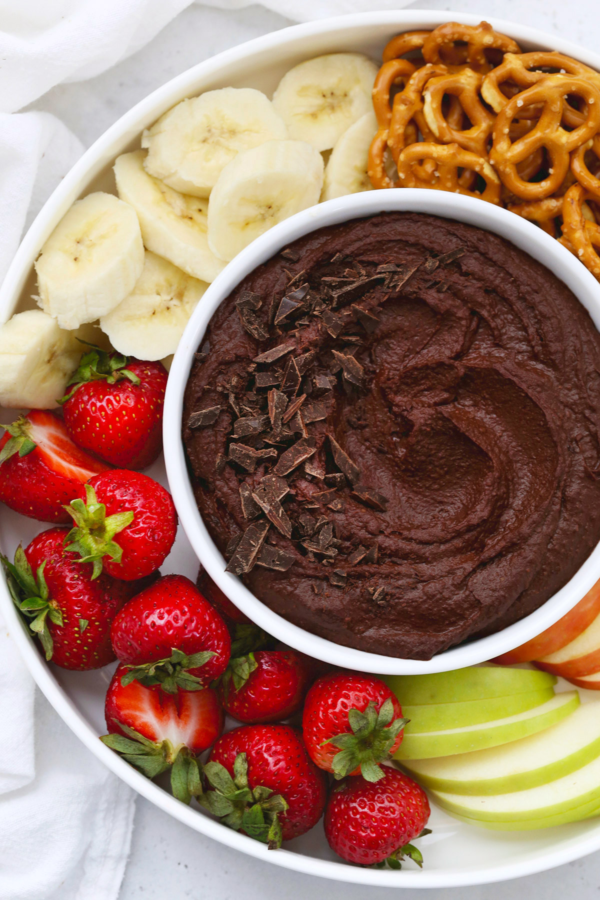 Chocolate Hummus in a white bowl surrounded by fruit