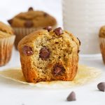 Gluten-Free Chocolate Chip Banana Muffins on a white background with chocolate chips scattered around them.
