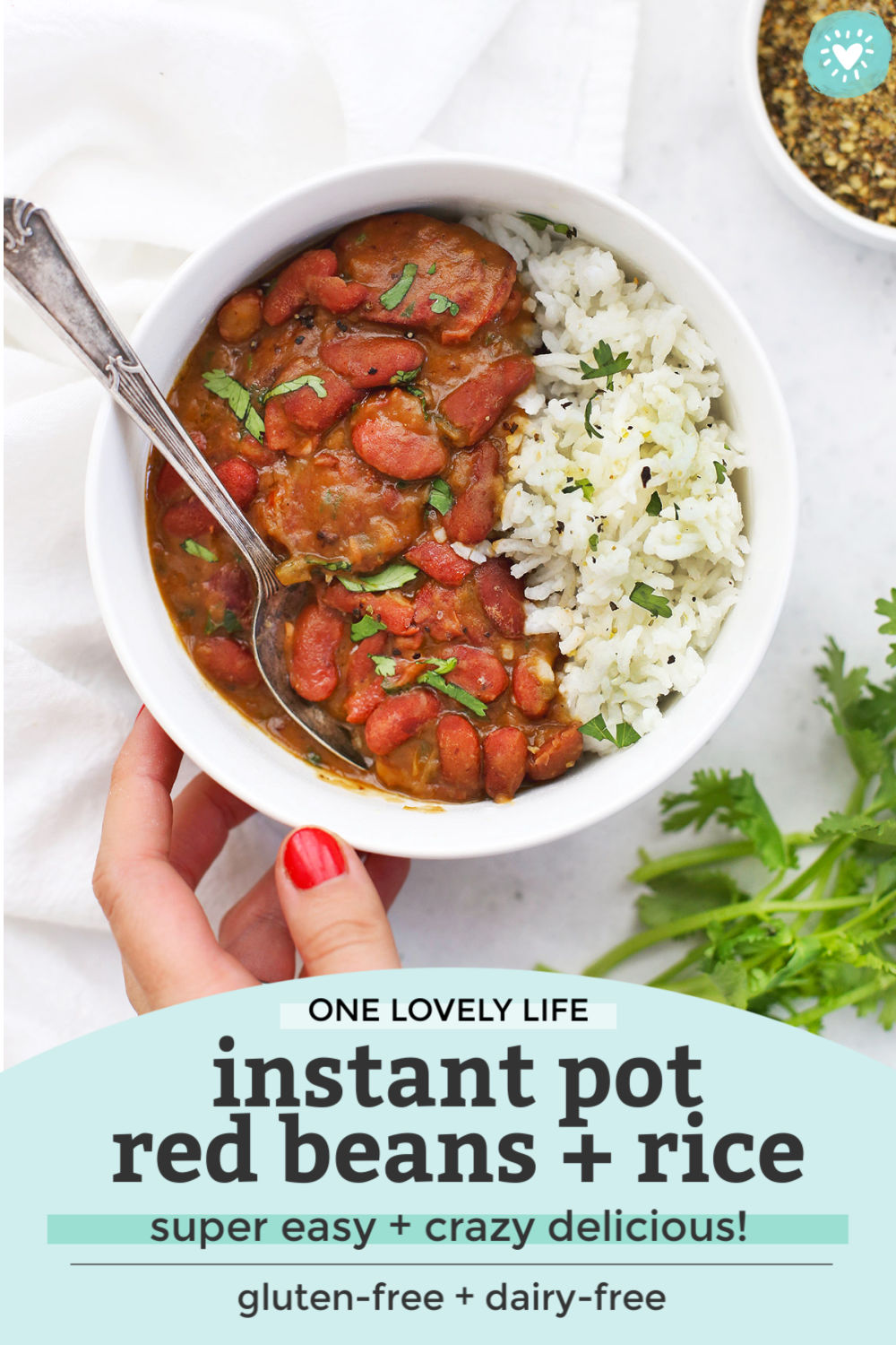 Serving Instant Pot Red Beans and Rice in a bowl garnished with fresh herbs with text overlay that reads "One Lovely Life Instant Pot Red Beans + Rice. Super Easy + Crazy Delicious! Gluten-free + dairy-free"
