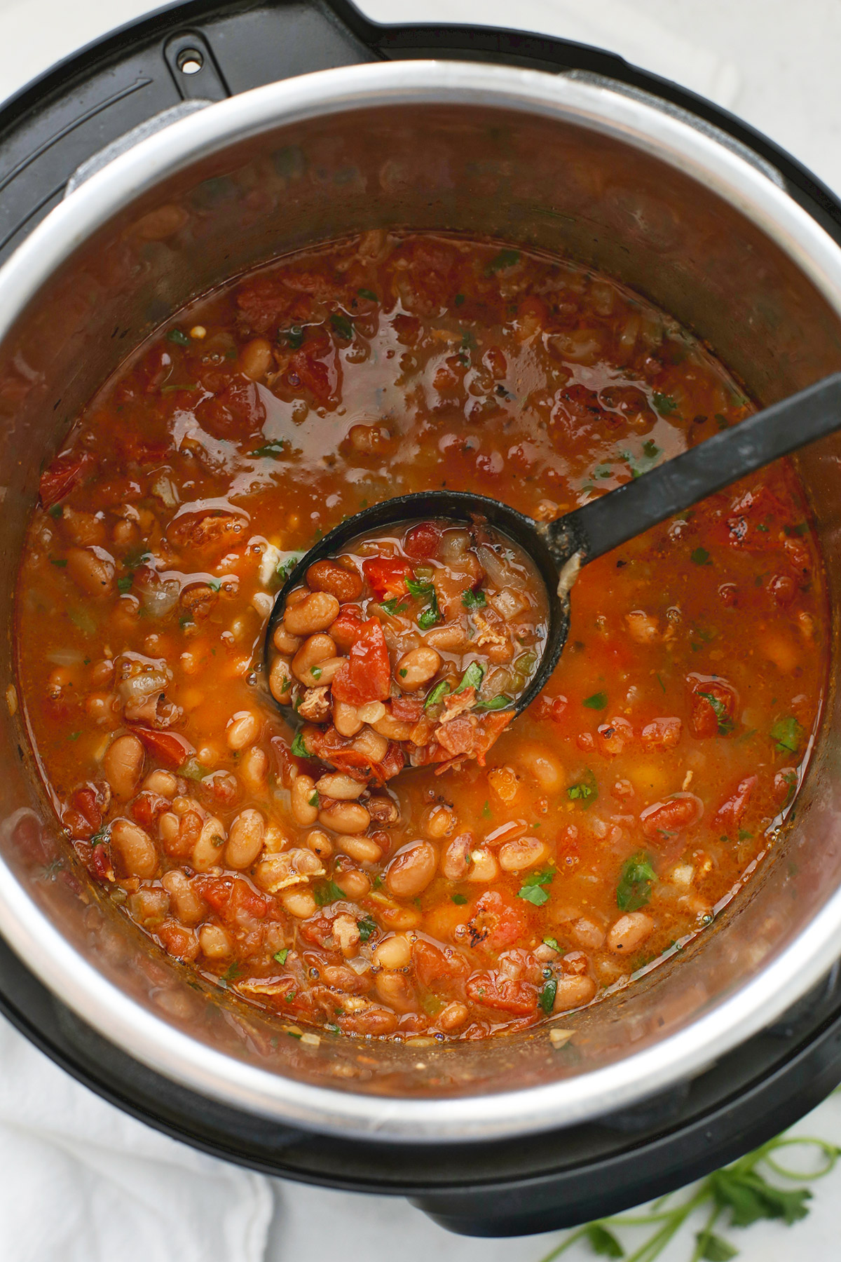 Scooping up Instant Pot Charro Beans in a black spoon
