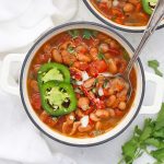 Two bowls of Instant Pot Charro Beans on a white background