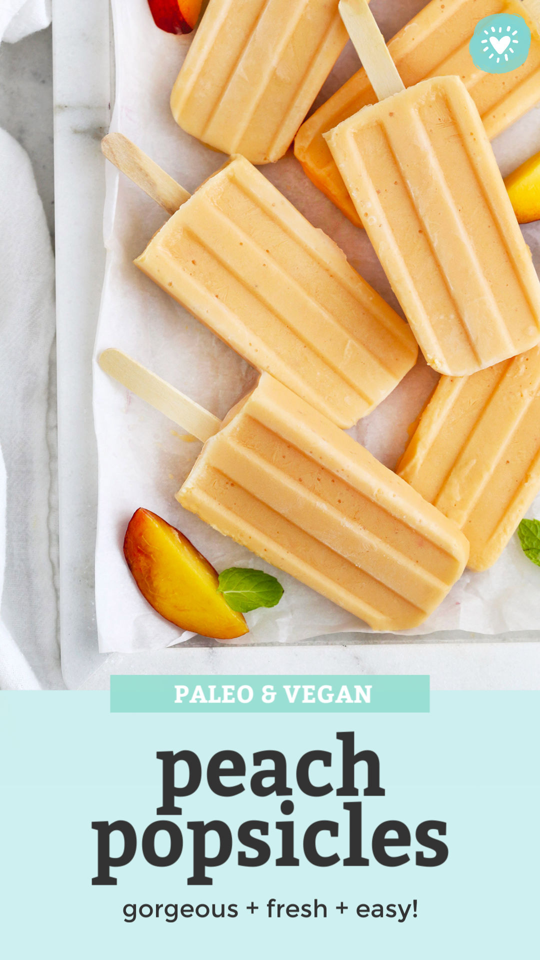 Overhead view of peach popsicles on a marble serving platter with peach slices and mint leaves with text overlay that reads "Paleo & Vegan Peach Popsicles. gorgeous + fresh + easy!"