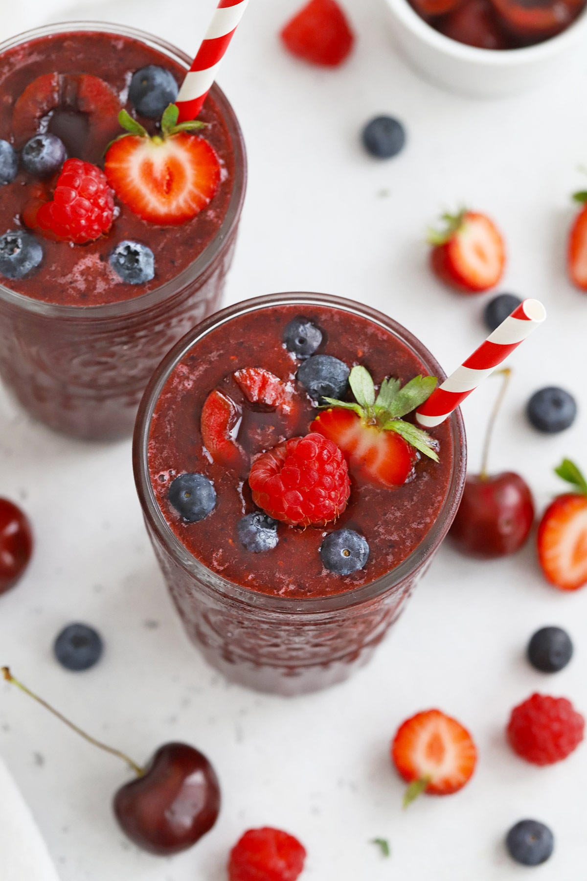 Cherry Berry Smoothies topped with fresh berries and red and white stripe straws