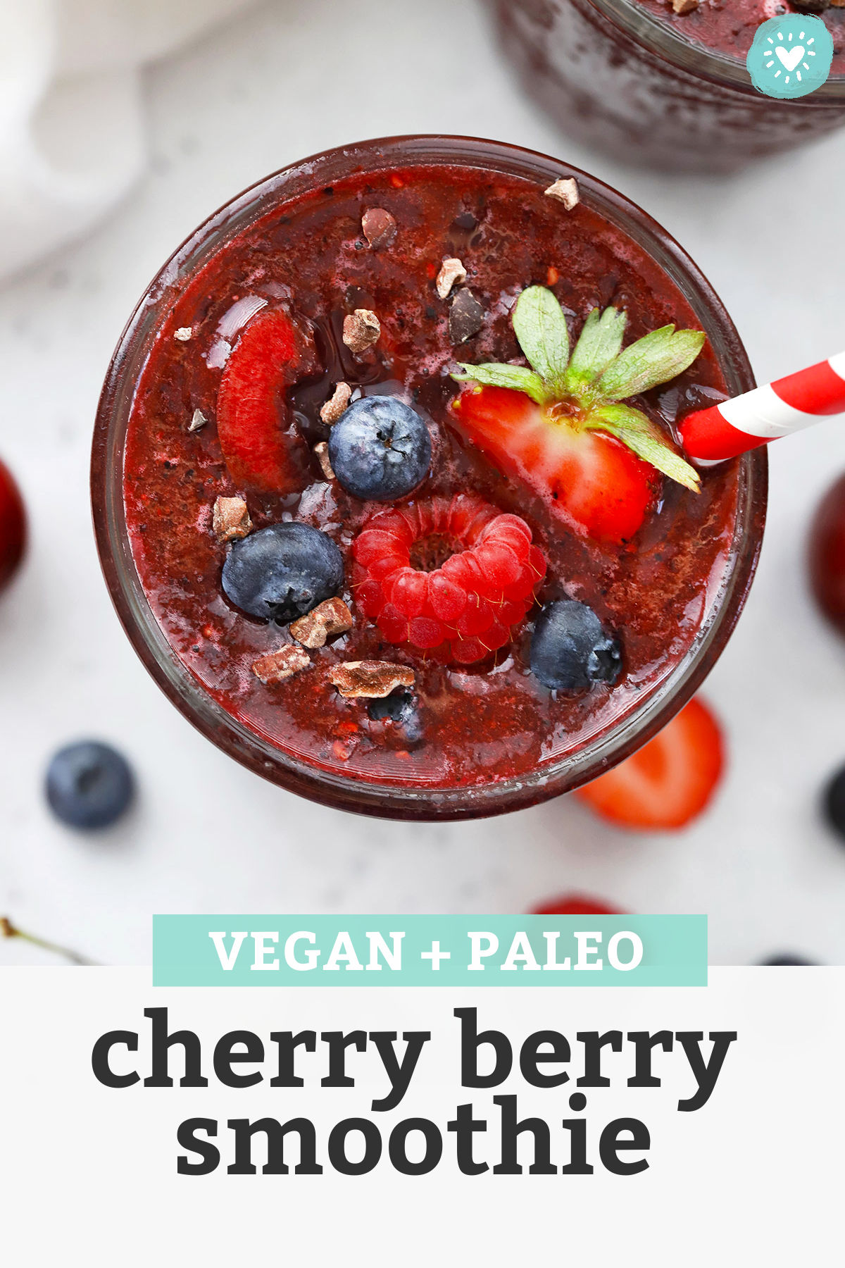 Close up view of a glass of vegan Cherry Berry Smoothie topped with fresh berries and cacao nibs with text overlay that reads "Vegan + Paleo Cherry Berry Smoothie"
