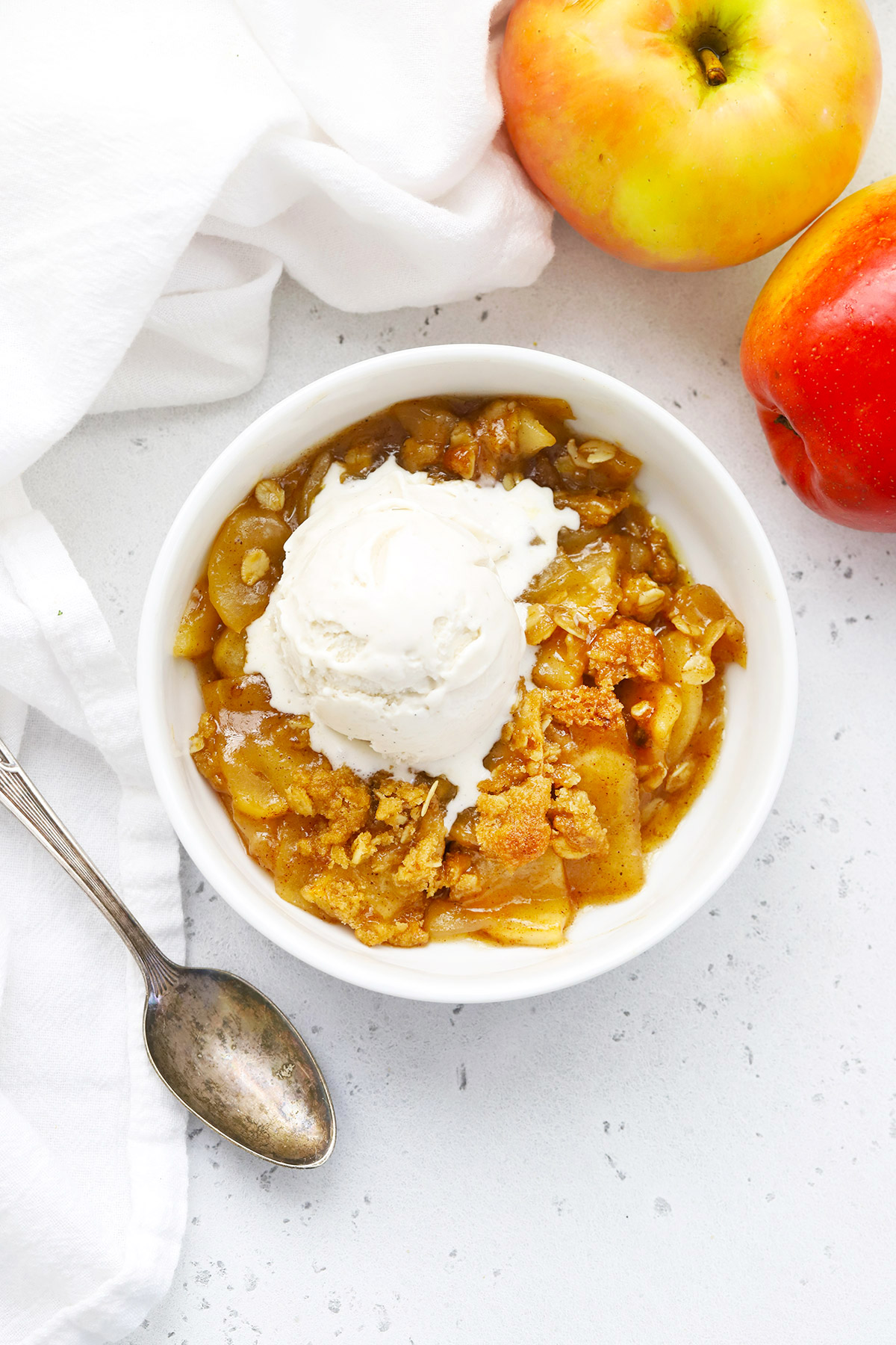 A bowl of gluten-free apple crisp with a scoop of dairy-free vanilla ice cream