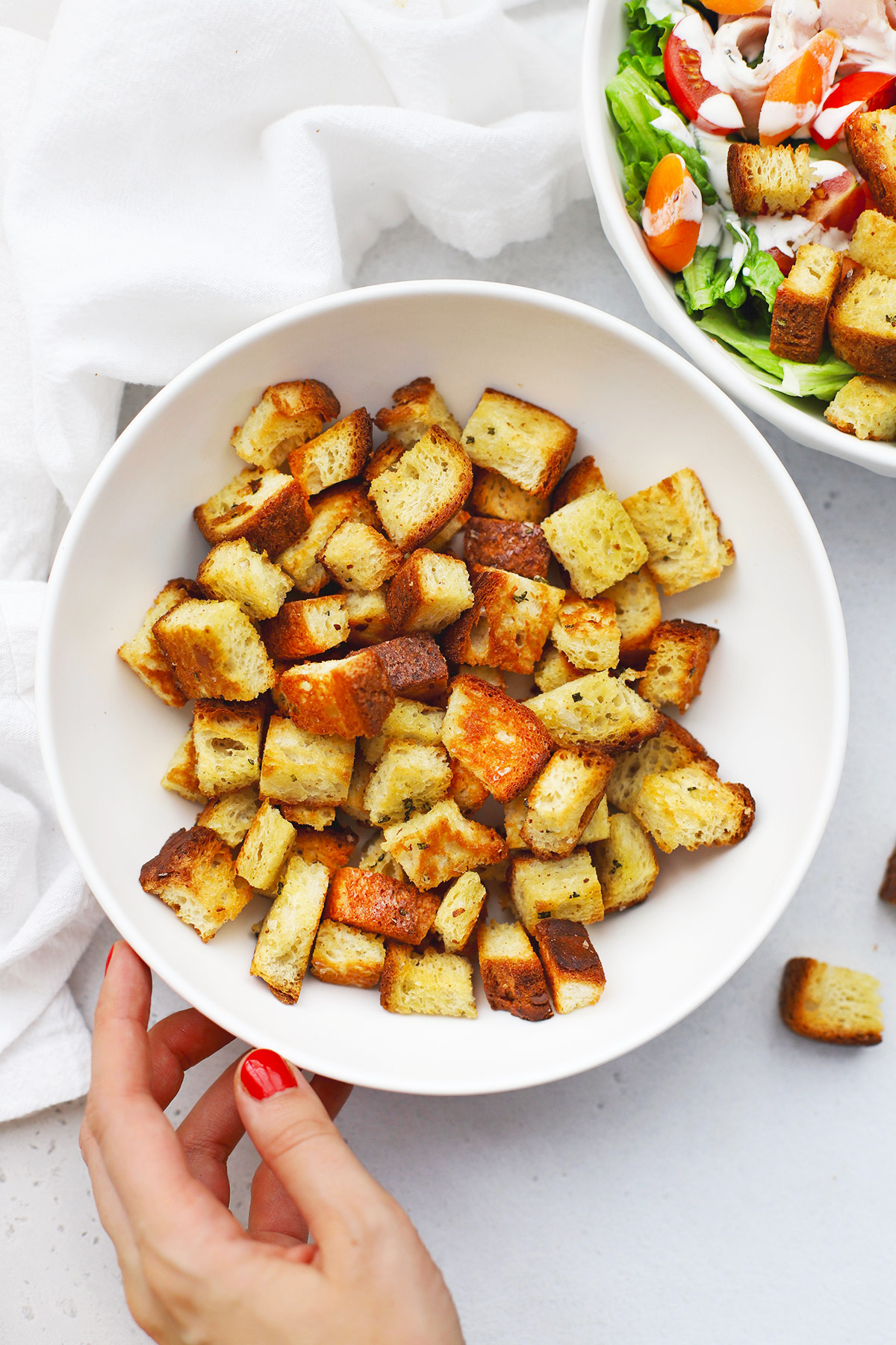 Setting down a bowl of gluten-free croutons next to a bowl of salad