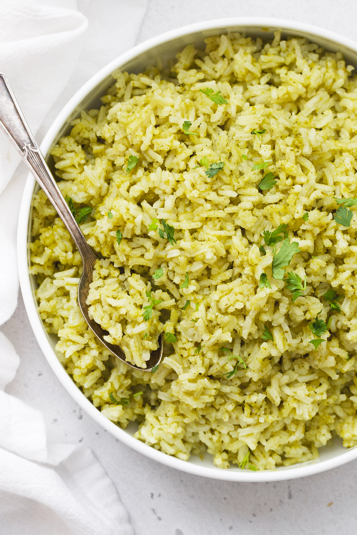 Close up view of Mexican Green Rice (Arroz Verde) in a white bowl on a white background