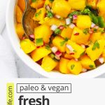 Close up view of fresh mango salsa in a white bowl with text overlay that reads "paleo & vegan fresh mango salsa: sweet + savory + spicy"