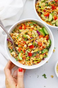 Setting down two bowls of Thai Quinoa Salad with Peanut Dressing