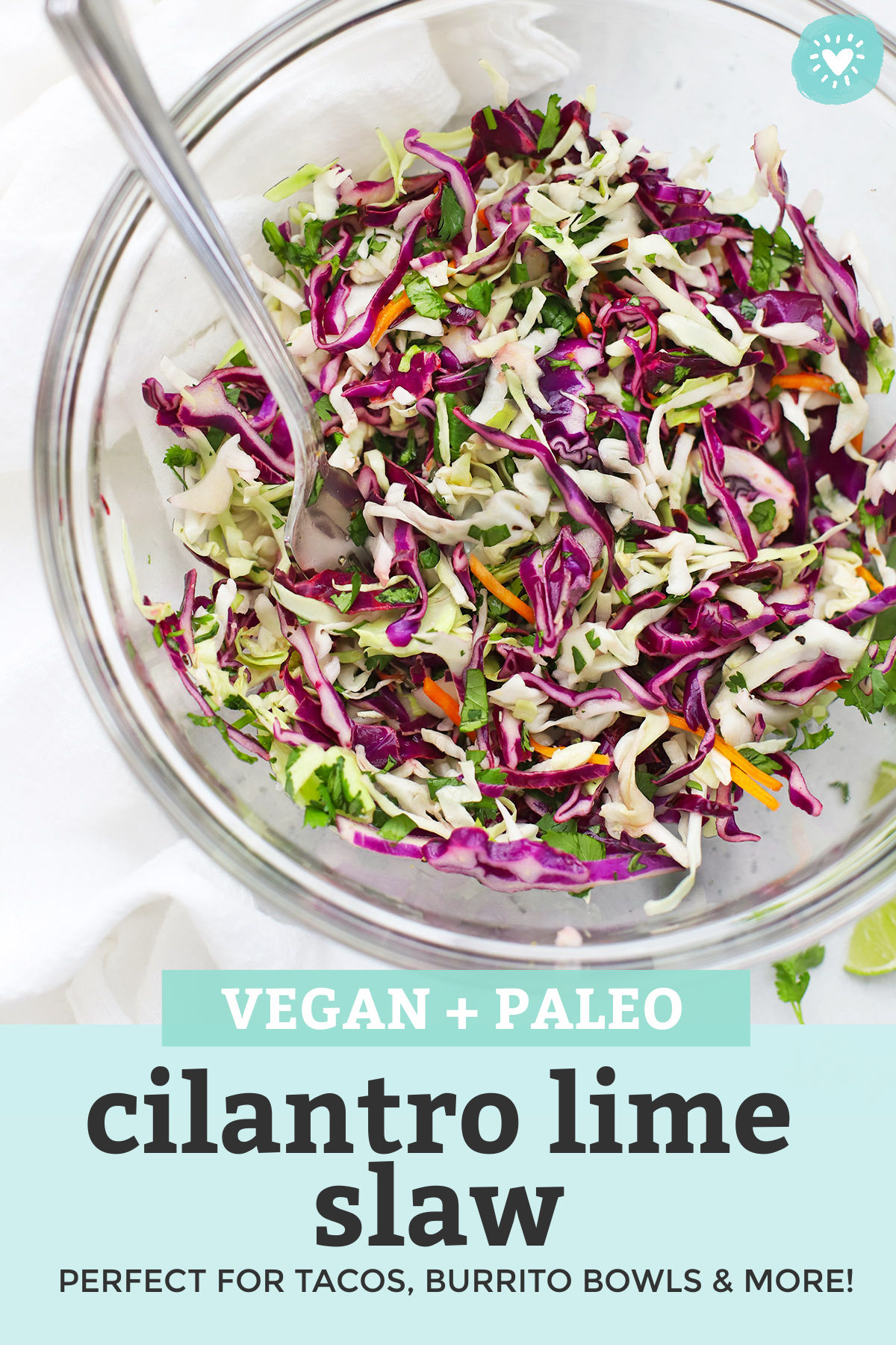 Close-up view of Cilantro Lime Slaw in a glass bowl with text overlay that reads "Vegan + Paleo Cilantro Lime Slaw. Perfect for tacos, burrito bowls, and more!"