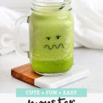 Green Monster Face Smoothie in a mason jar glass with a black and white striped straw with text overlay that reads "Cute + Fun + Easy Monster Smoothies"
