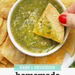 Close up view of a tortilla chip being dipped into homemade salsa verde (green salsa) with text overlay that reads "Easy + Delicious Homemade Salsa Verde"