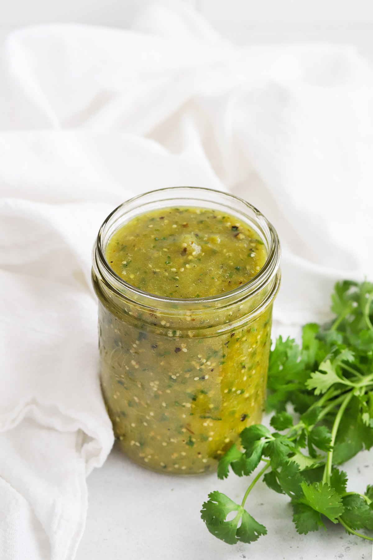 Jar of Homemade Salsa Verde (Green Salsa) with fresh cilantro on the side.