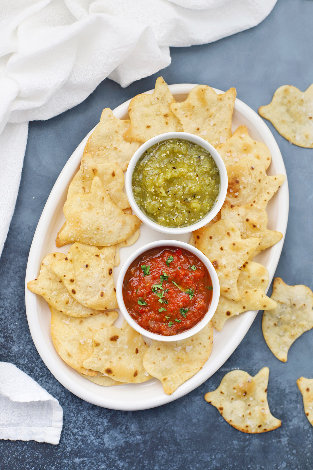 Baked Ghost Chips on a platter with bowls of red and green salsa
