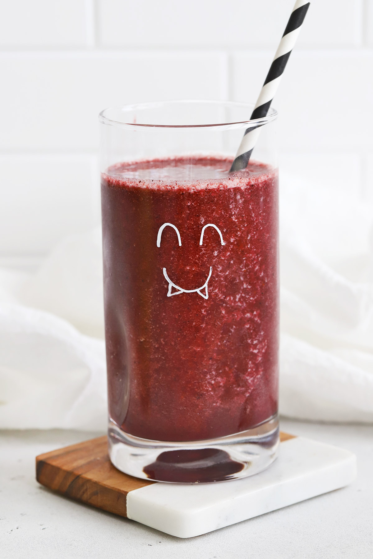 Blueberry Peach Smoothie in a glass with a monster face drawn on the glass