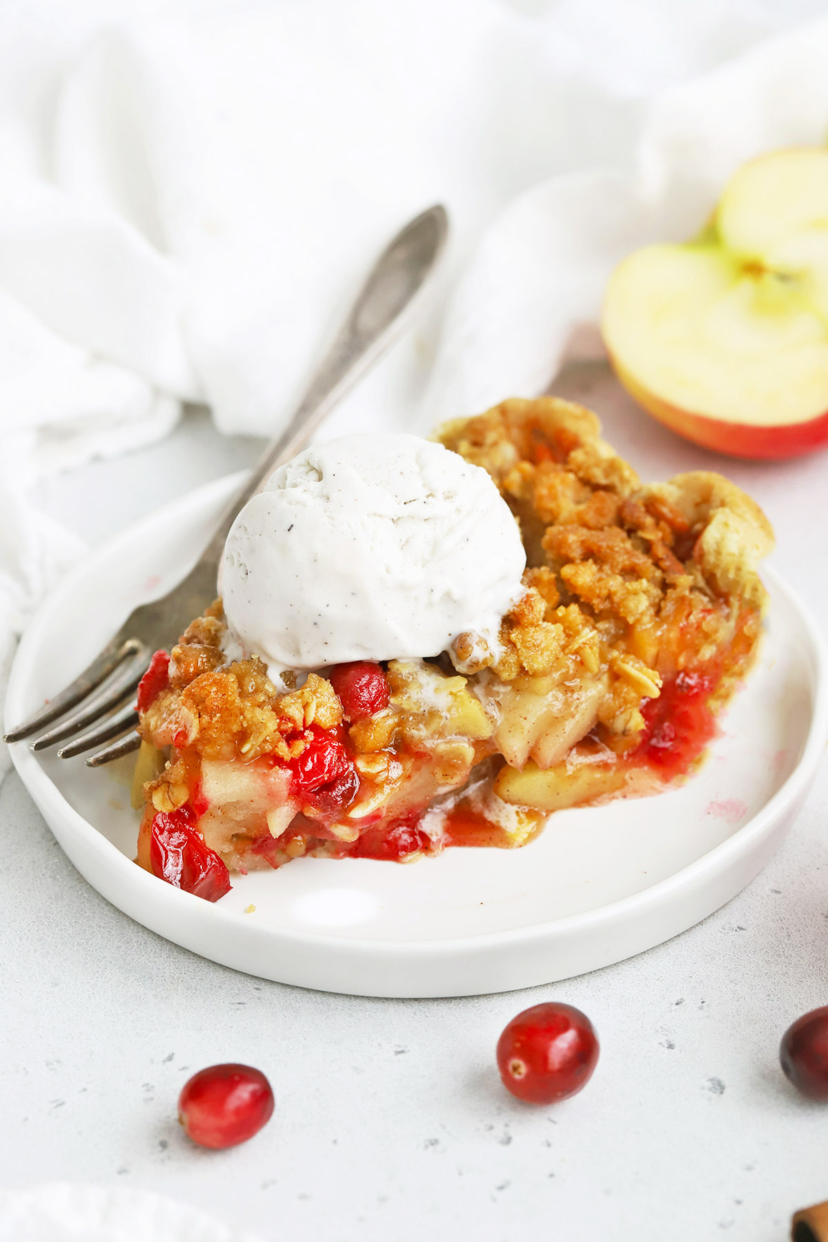 Front view of a slice of Apple Cranberry Crumble Pie on a white plate