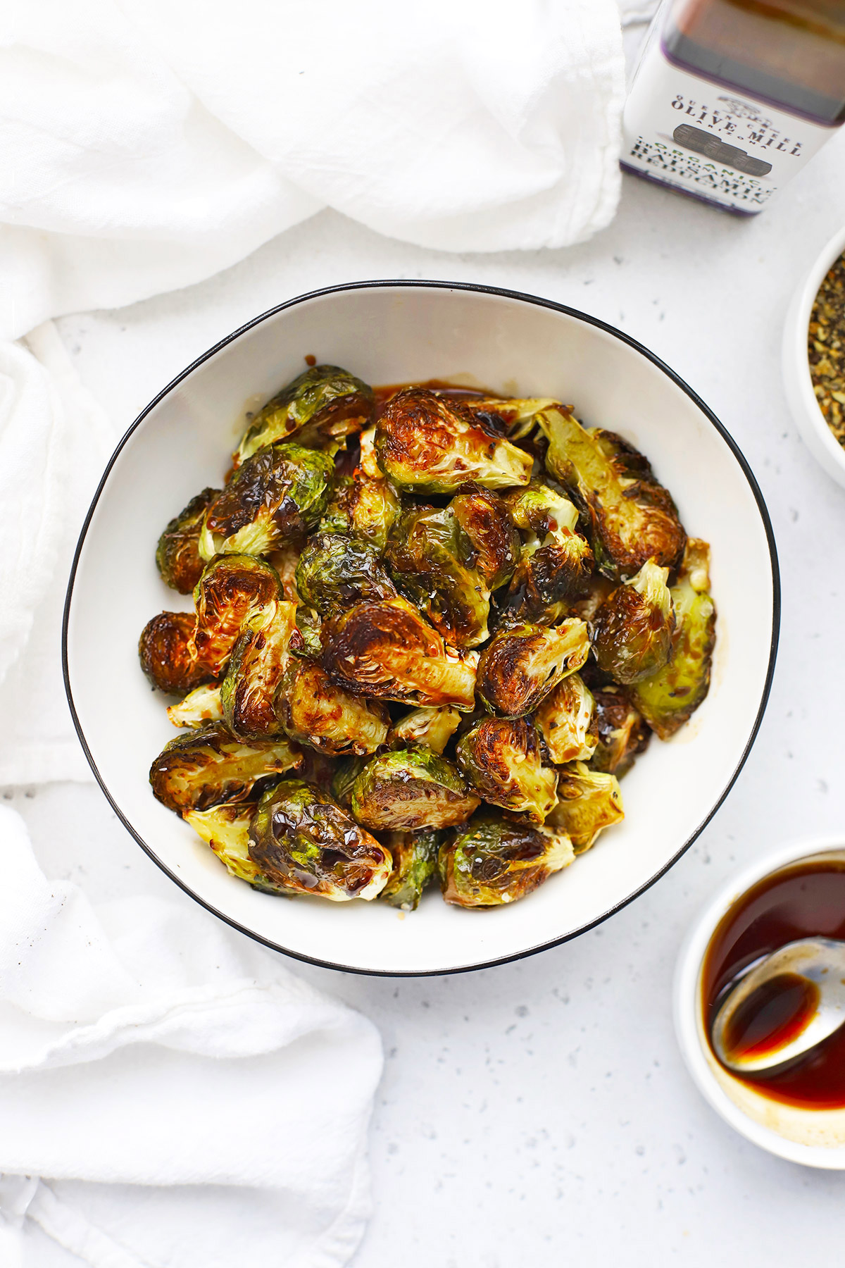 Overhead view of a bowl of roasted Balsamic Brussels Sprouts on a white background.
