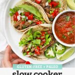 Overhead view of a plate of slow cooker barbacoa beef tacos with salsa and avocado with text overlay that reads "Gluten-Free + Paleo Slow Cooker Barbacoa Beef"
