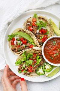 Overhead view of a plate of slow cooker barbacoa beef tacos with salsa and avocado