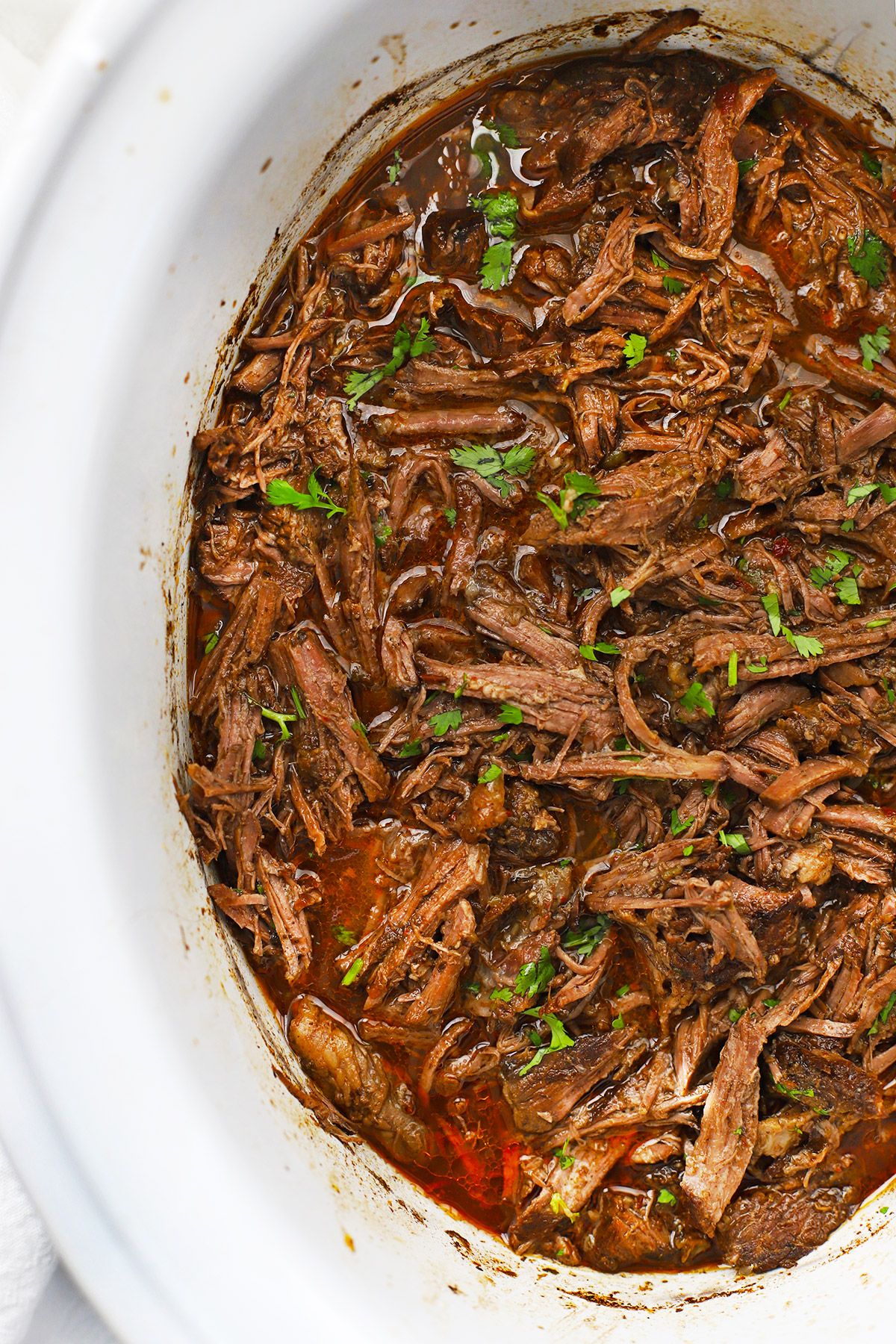 Overhead view of a slow cooker full of barbacoa beef